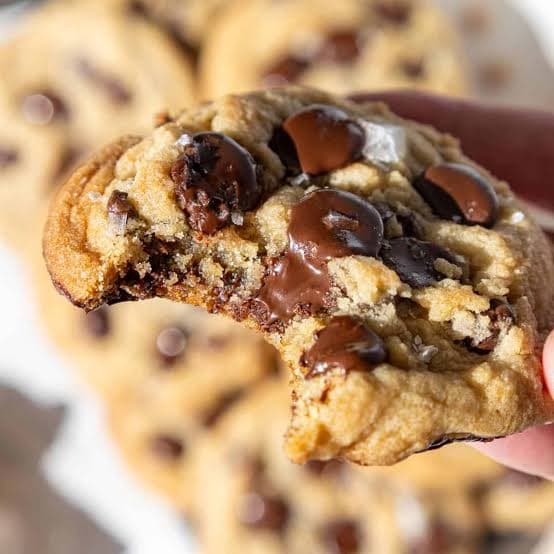 A warm brown butter chocolate chip cookie with a bite taken out